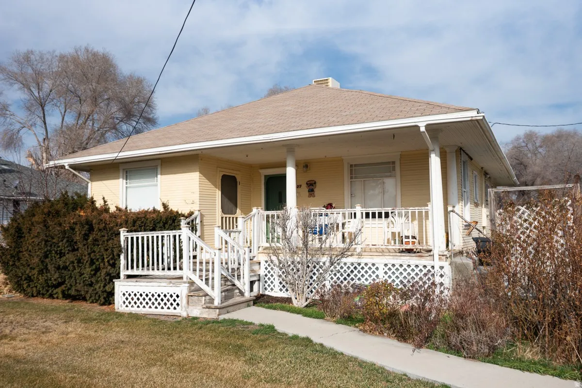 Bungalow featuring a porch, roof with shingles, a front lawn, and a chimney