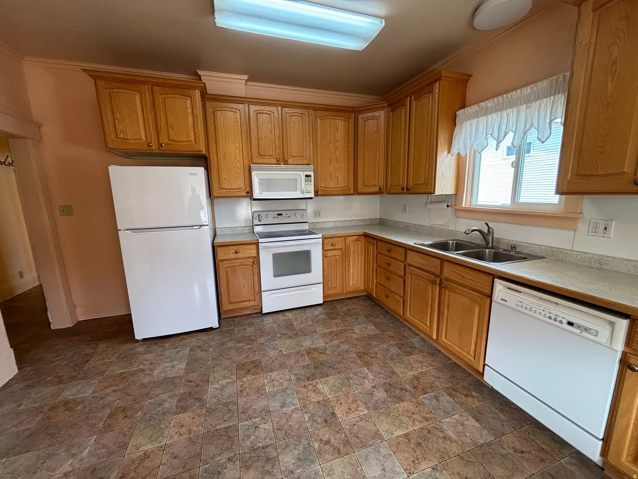 Kitchen with stone finish flooring, light countertops, white appliances, and wood finish cabinets