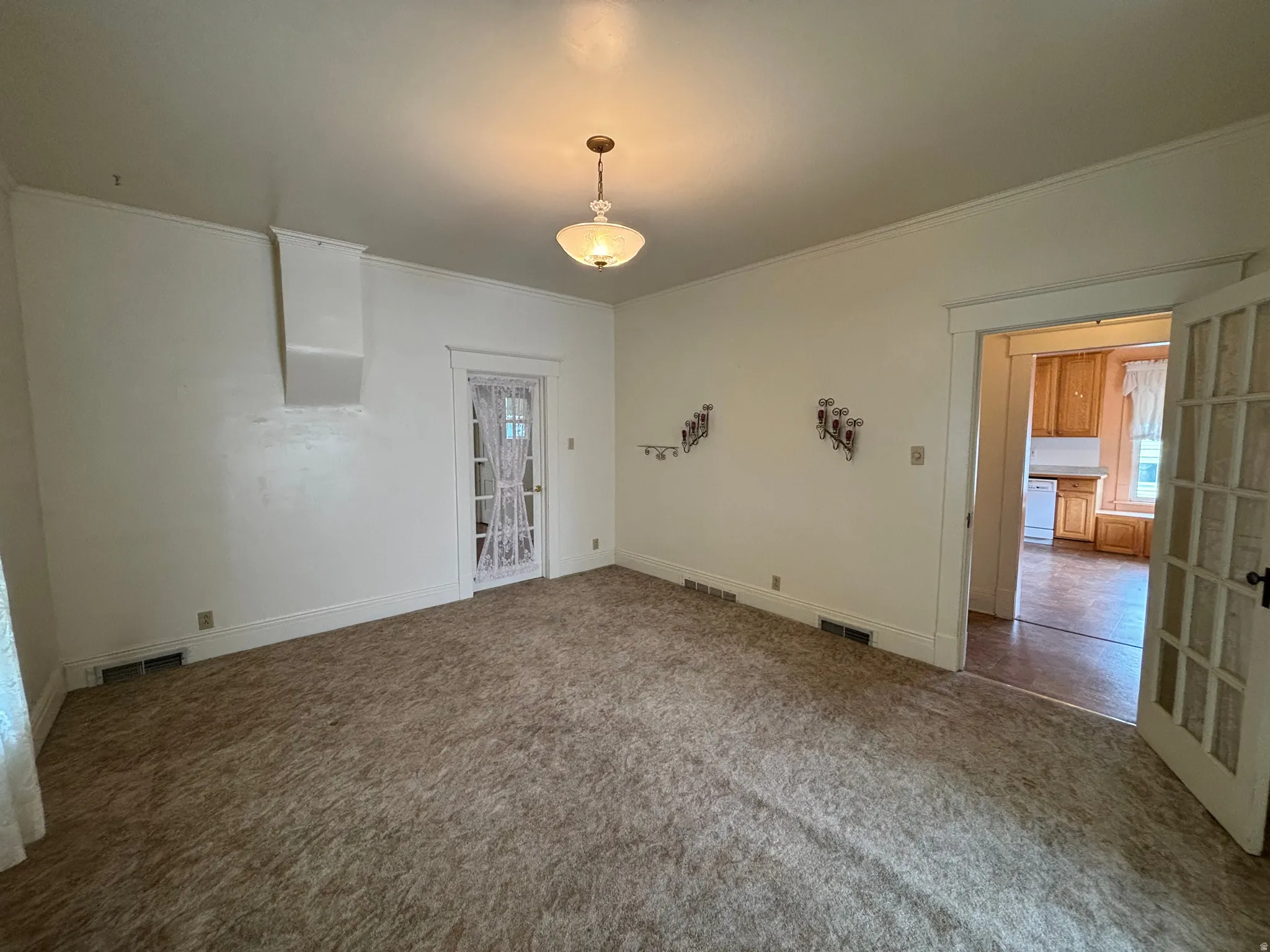 Carpeted empty room featuring crown molding and baseboards