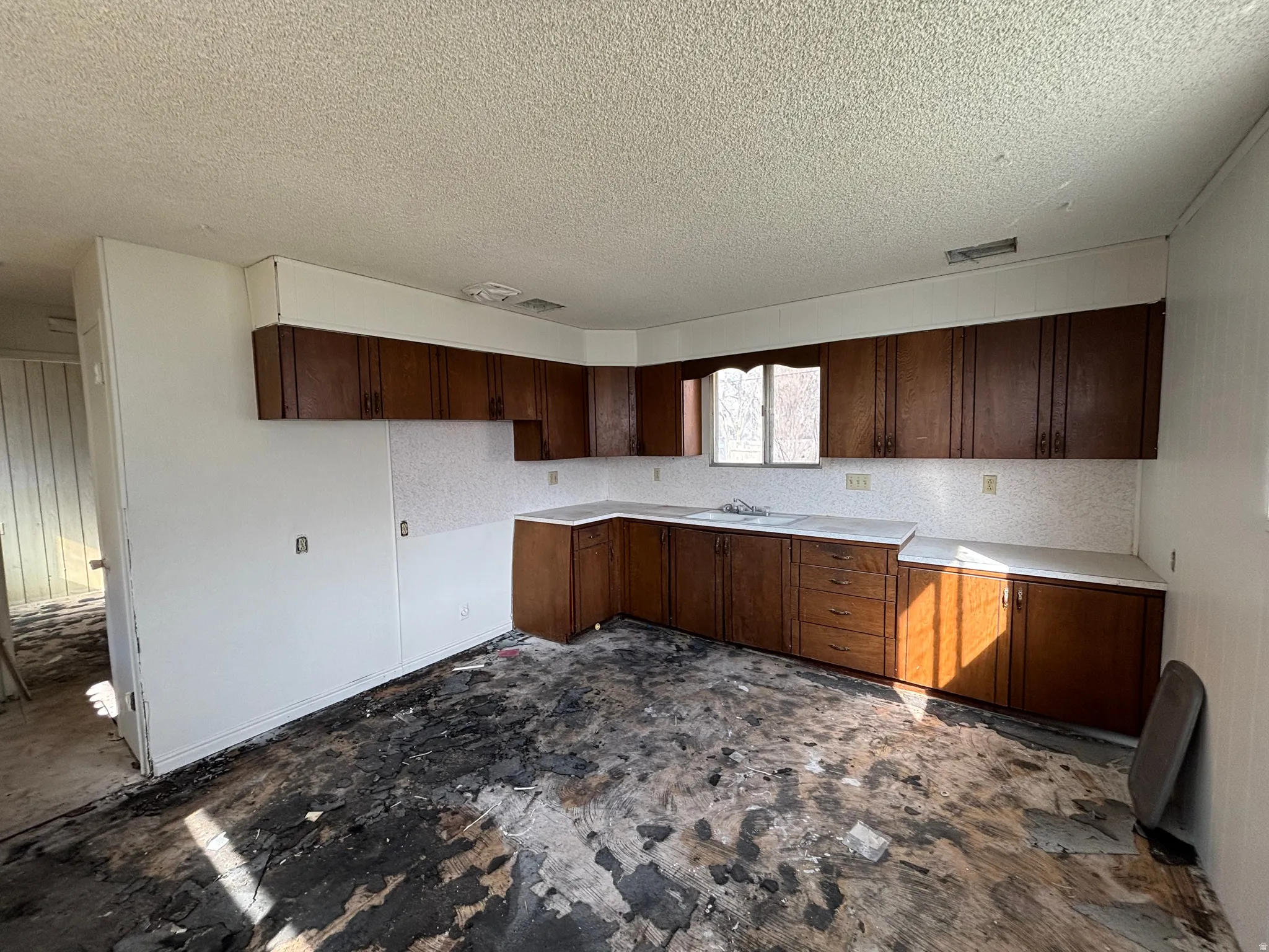 Kitchen featuring dark wood finish cabinetry, light countertops, and a textured ceiling