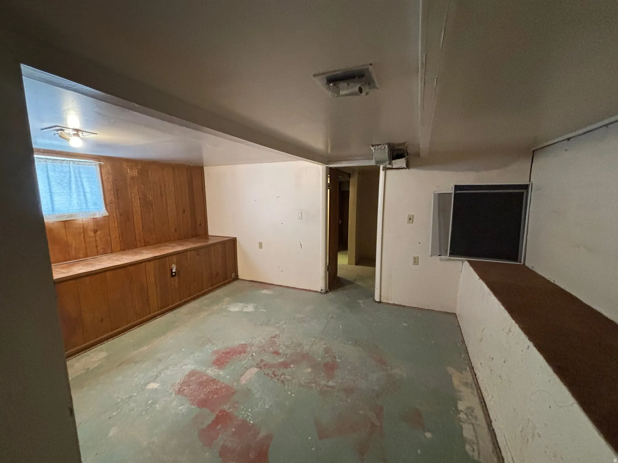 Additional living space featuring wooden walls and concrete flooring