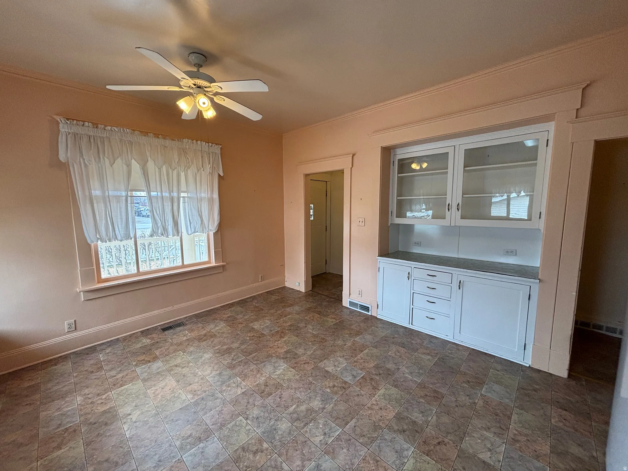 Interior space featuring stone finish floors, ceiling fan, and crown molding