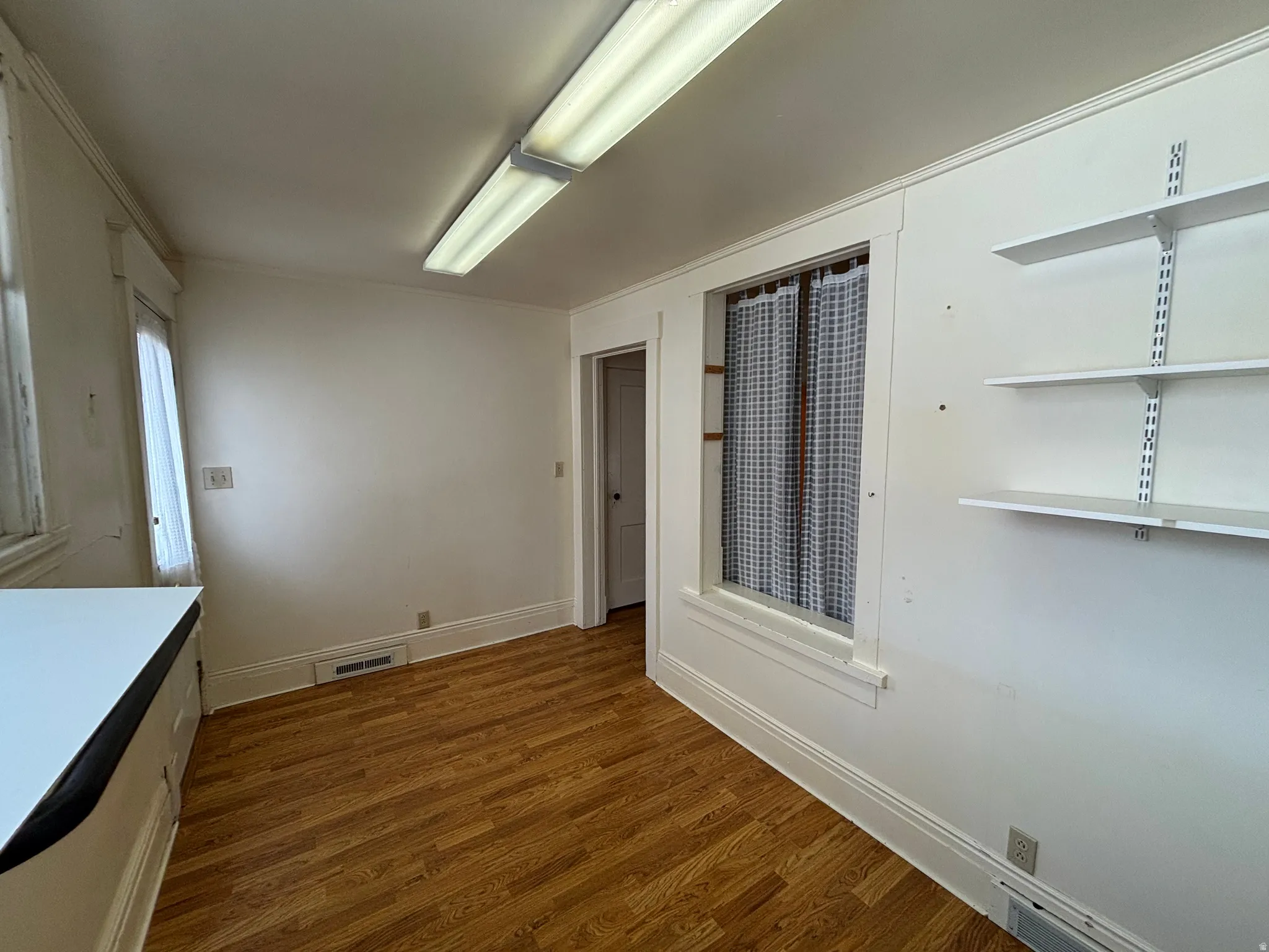 Unfurnished dining area with dark wood-type flooring and baseboards