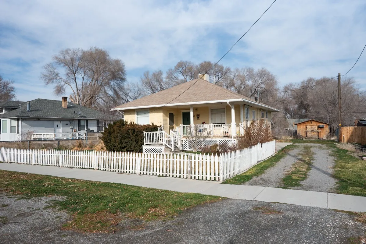 View of front of property featuring covered porch, a fenced front yard, driveway, and a chimney