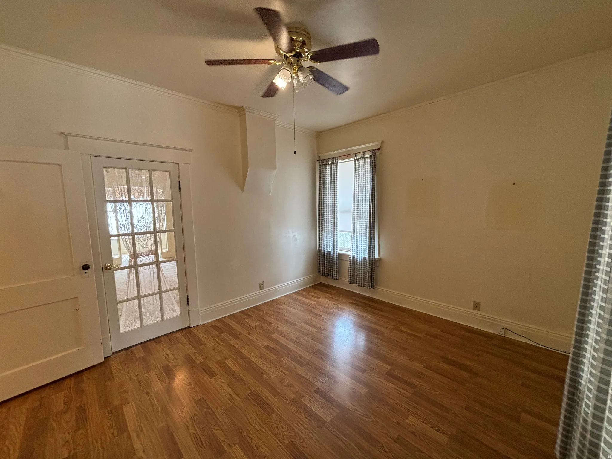 Unfurnished room with wood finished floors, a ceiling fan, and crown molding