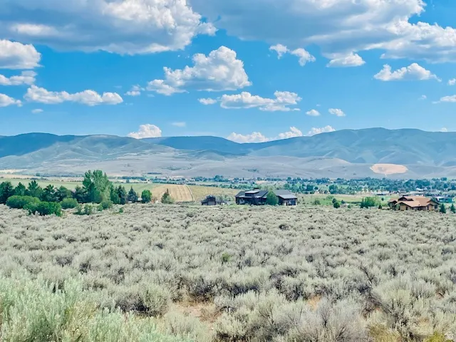 Expansive landscape featuring distant mountains, a wide valley, and scattered residential properties