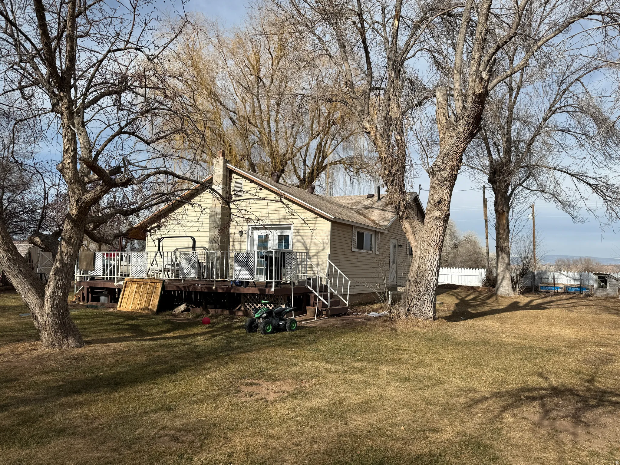 View of home's exterior featuring a yard, a chimney, a wooden deck, and stairs