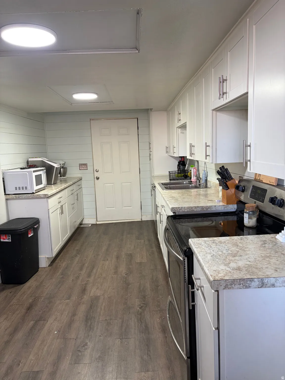 Kitchen featuring electric stove, white cabinets, light countertops, and dark wood finished floors