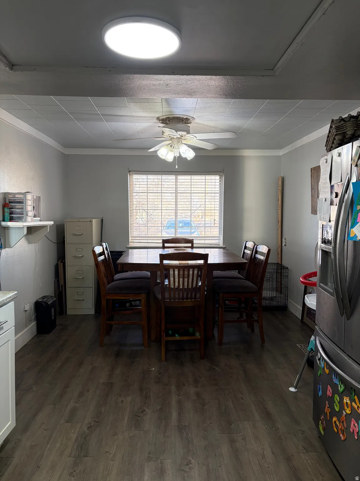 Dining area with dark wood-style floors, crown molding, and a ceiling fan