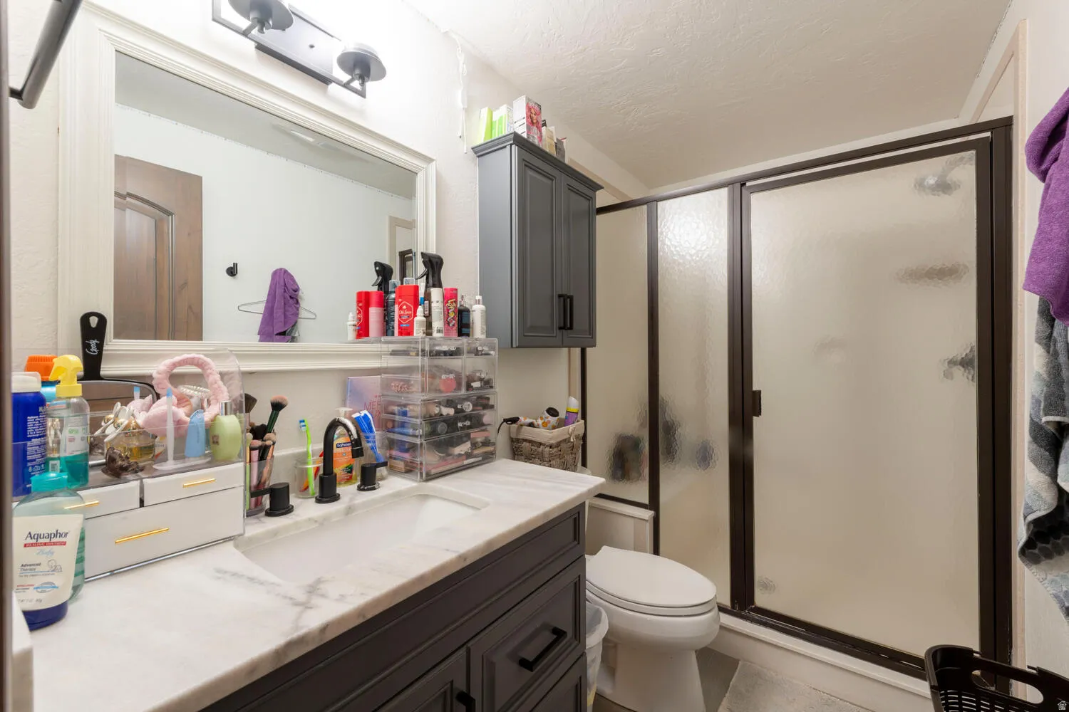 Bathroom with vanity, a stall shower, and a textured ceiling
