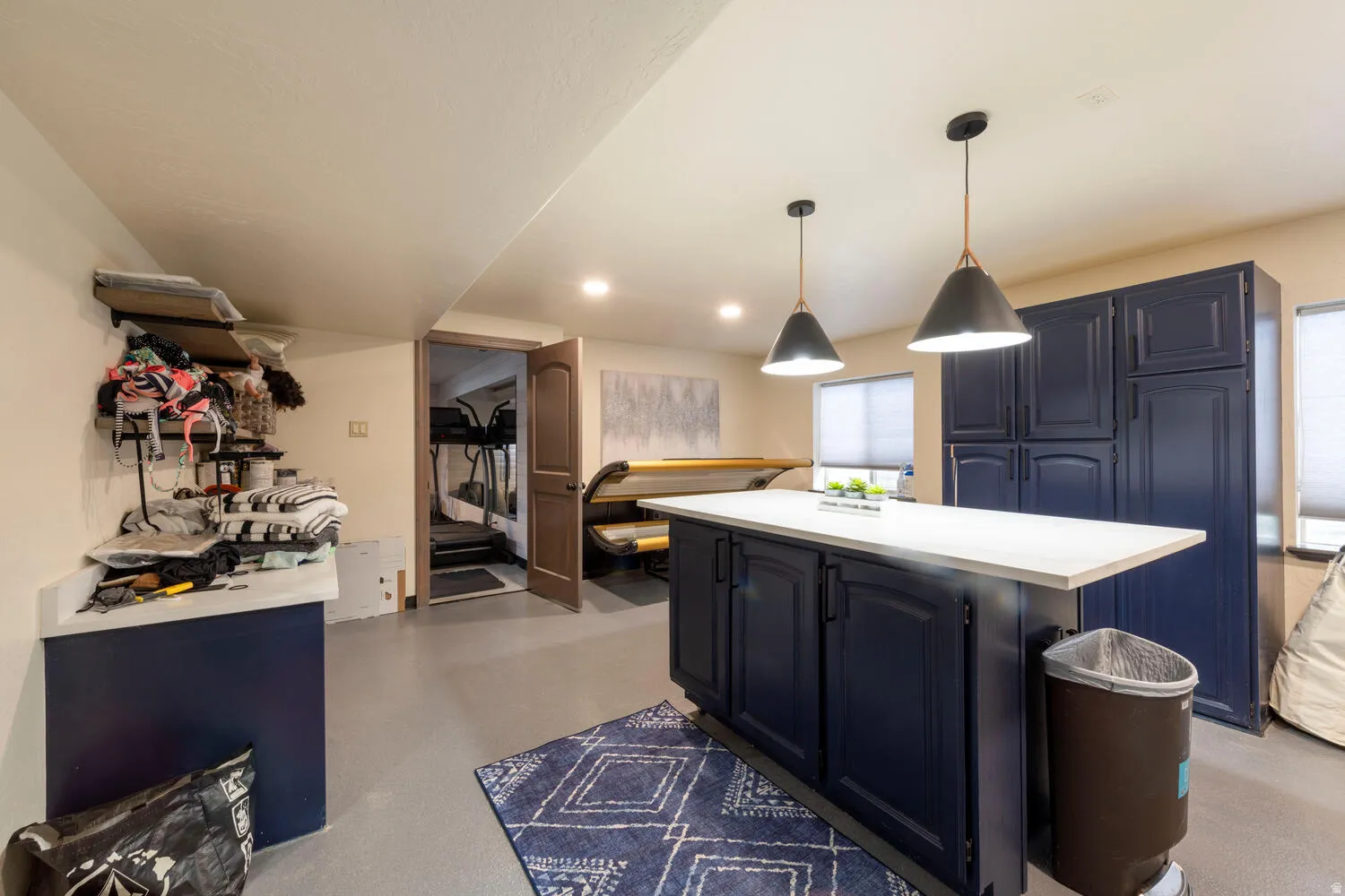 Kitchen with light countertops, decorative light fixtures, blue cabinetry, finished concrete floors, and a kitchen island