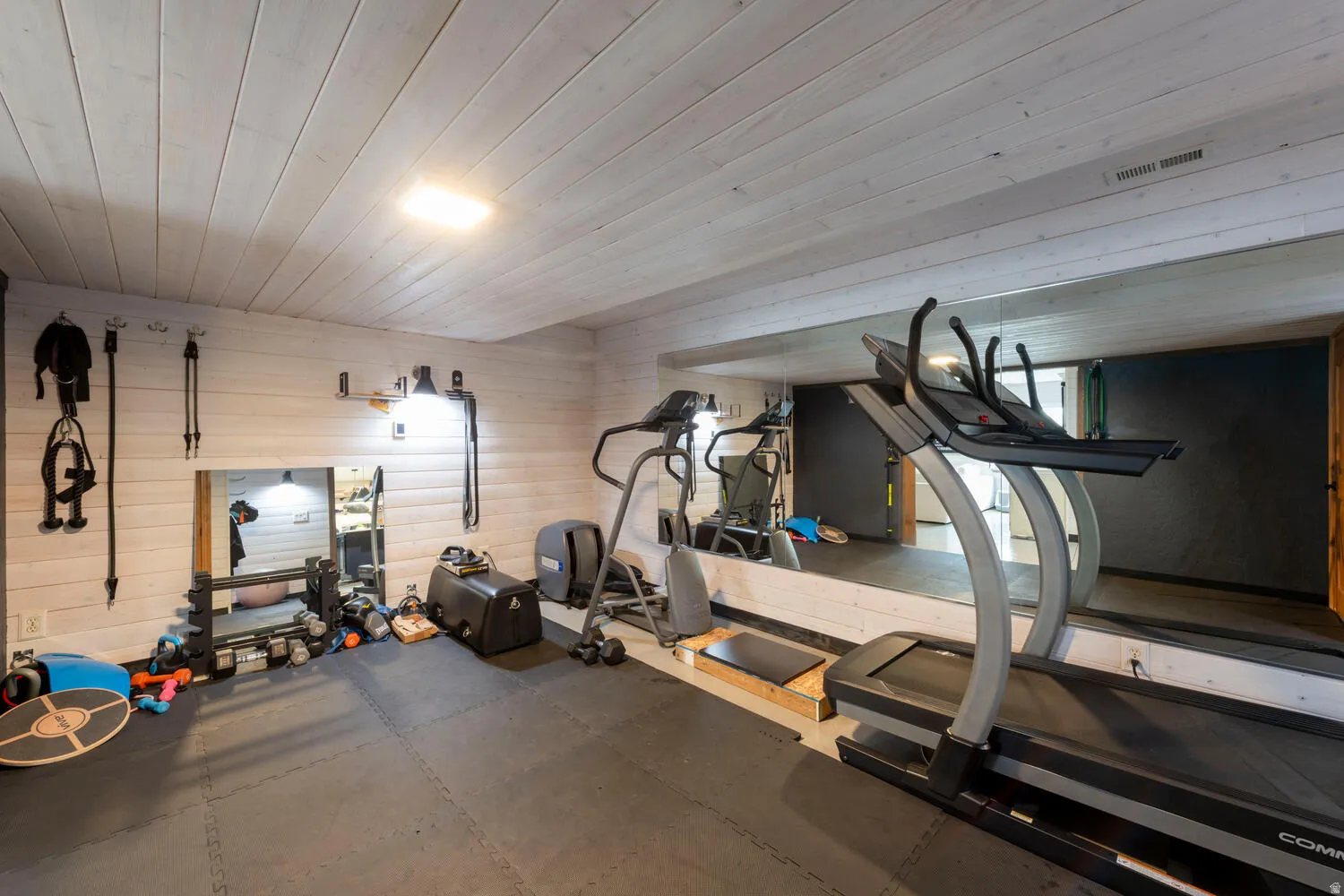 Exercise area featuring wood ceiling, rubber floors, and wood walls
