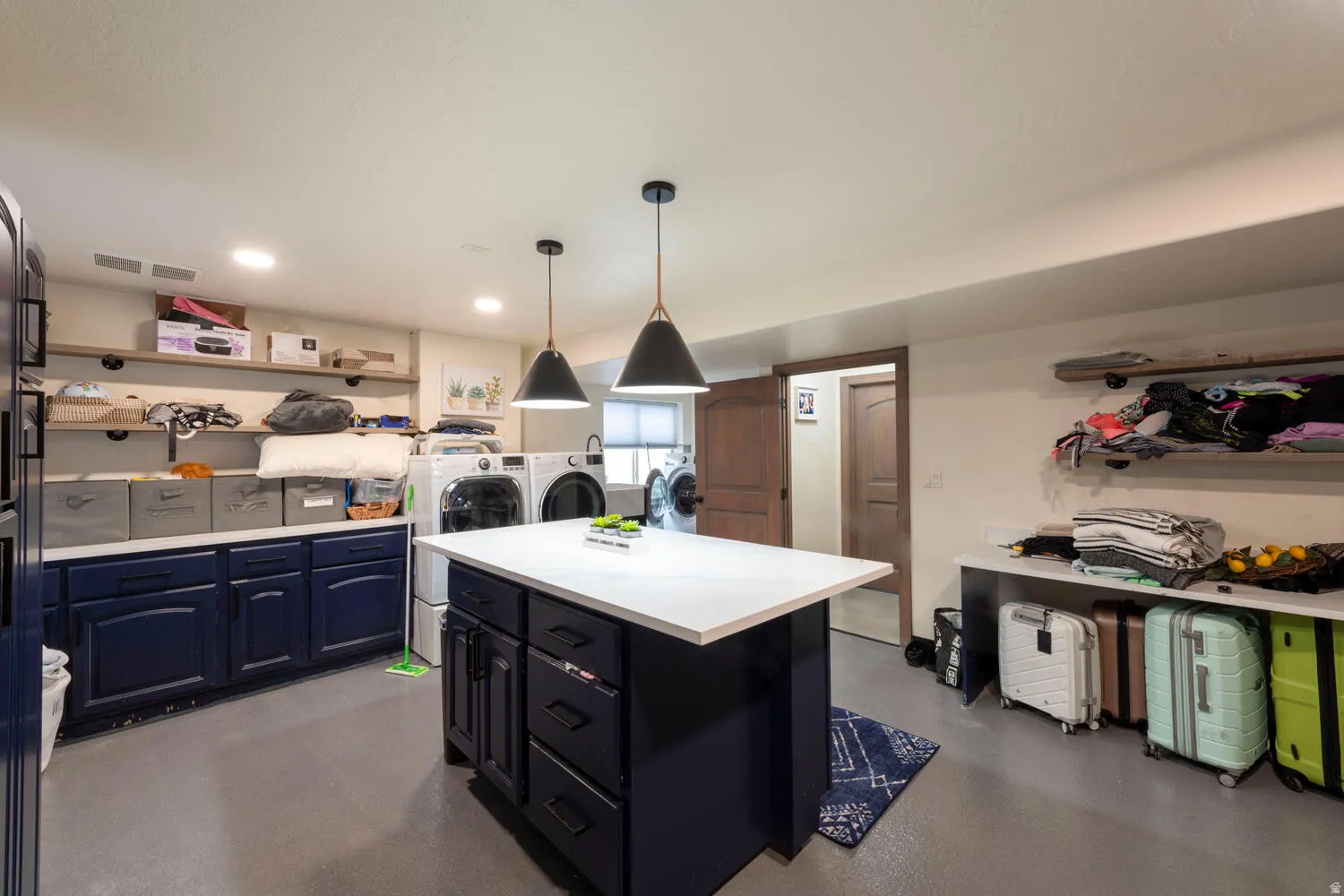Kitchen with open shelves, light countertops, pendant lighting, a center island, and independent washer and dryer