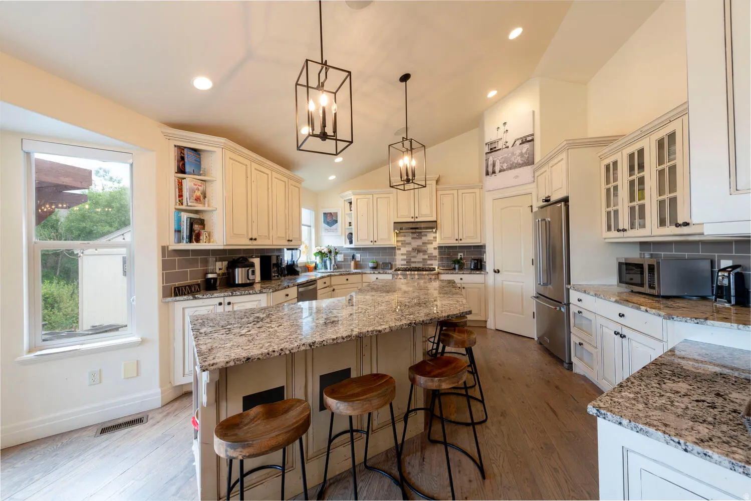 Kitchen with decorative backsplash, a breakfast bar, vaulted ceiling, hanging light fixtures, and light stone countertops