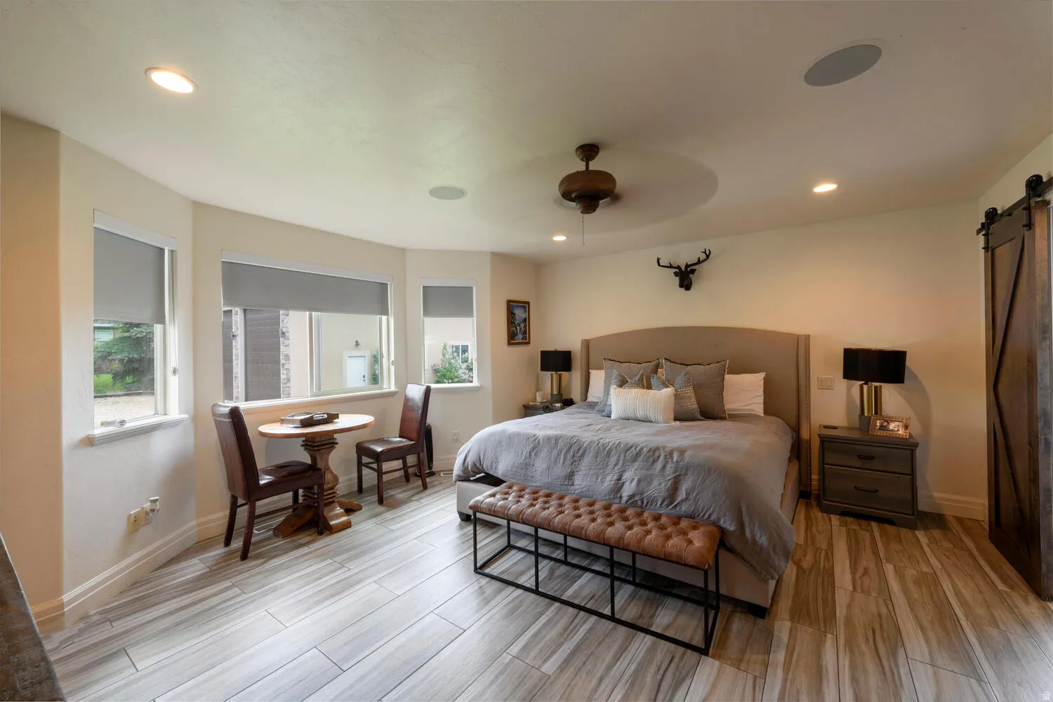 Bedroom with a barn door, wood tiled floors, ceiling fan, and recessed lighting