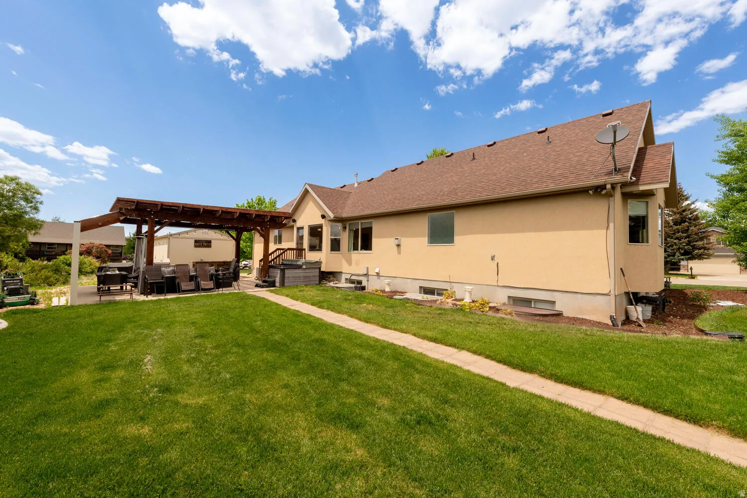 Rear view of property with a pergola, a patio, a lawn, and stucco siding