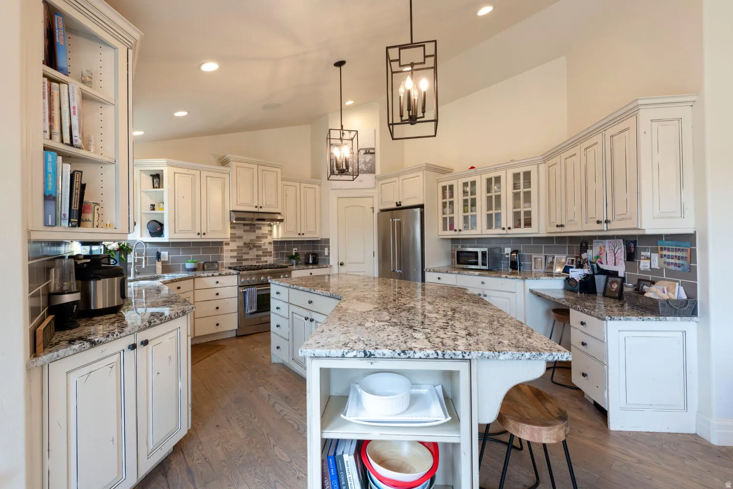 Kitchen featuring lofted ceiling, open shelves, a breakfast bar area, light wood-style flooring, and pendant lighting