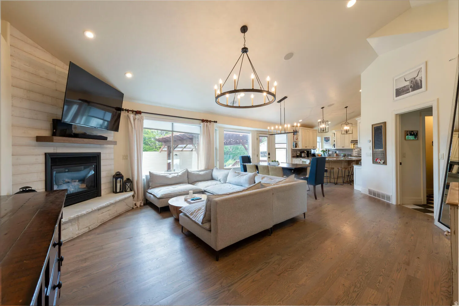 Living room featuring dark wood-type flooring, a large fireplace, a chandelier, recessed lighting, and high vaulted ceiling