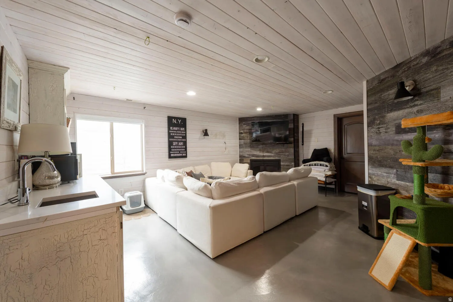 Living area with a fireplace, wooden walls, finished concrete floors, and wooden ceiling