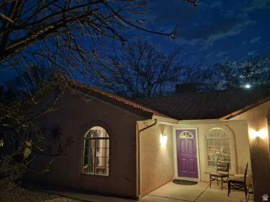 Property exterior at night with stucco siding and a chimney