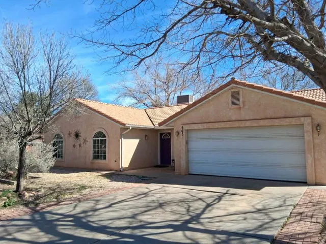 View of front facade with a tile roof, concrete driveway, stucco siding, a garage, and a chimney