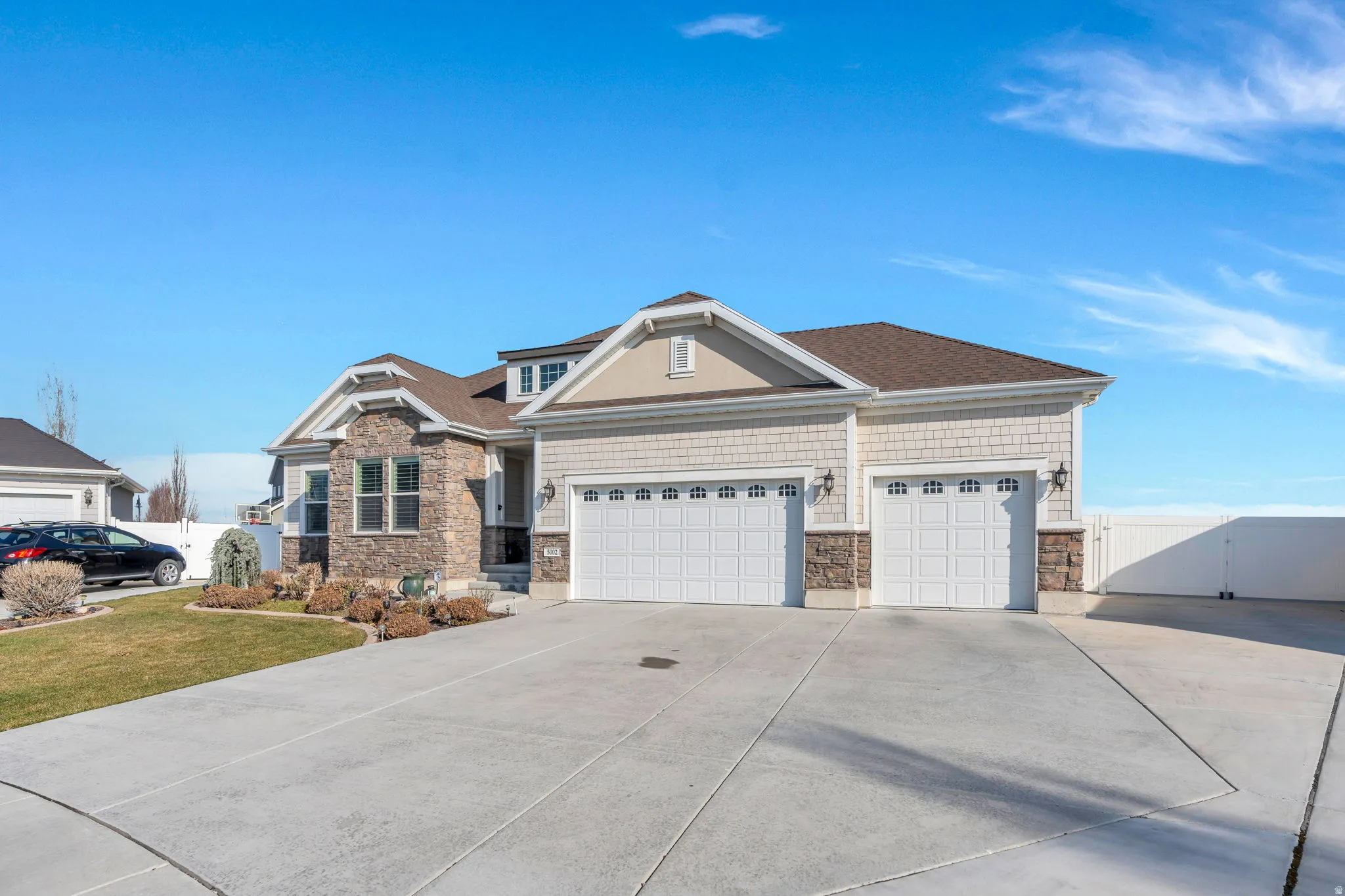 Craftsman inspired home with stone siding, driveway, an attached garage, and a gate