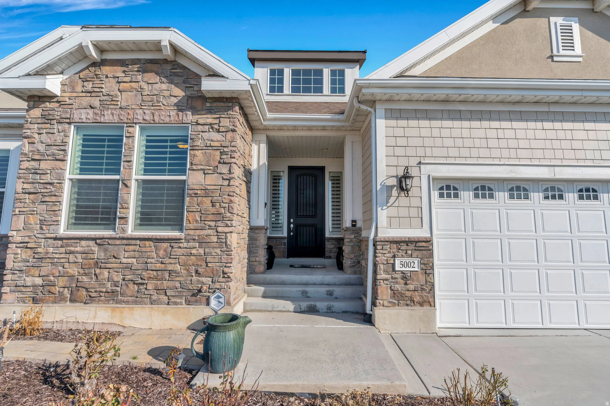 Property entrance featuring stone siding, driveway, and a garage