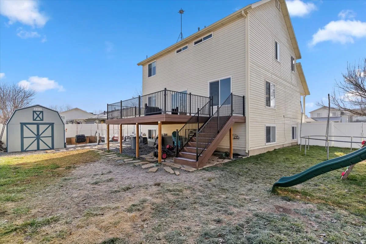 Rear view of property featuring stairs, a deck, a fenced backyard, and a storage shed