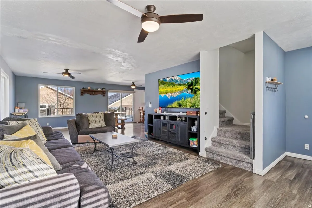 Living room featuring stairs, dark wood finished floors, and ceiling fan