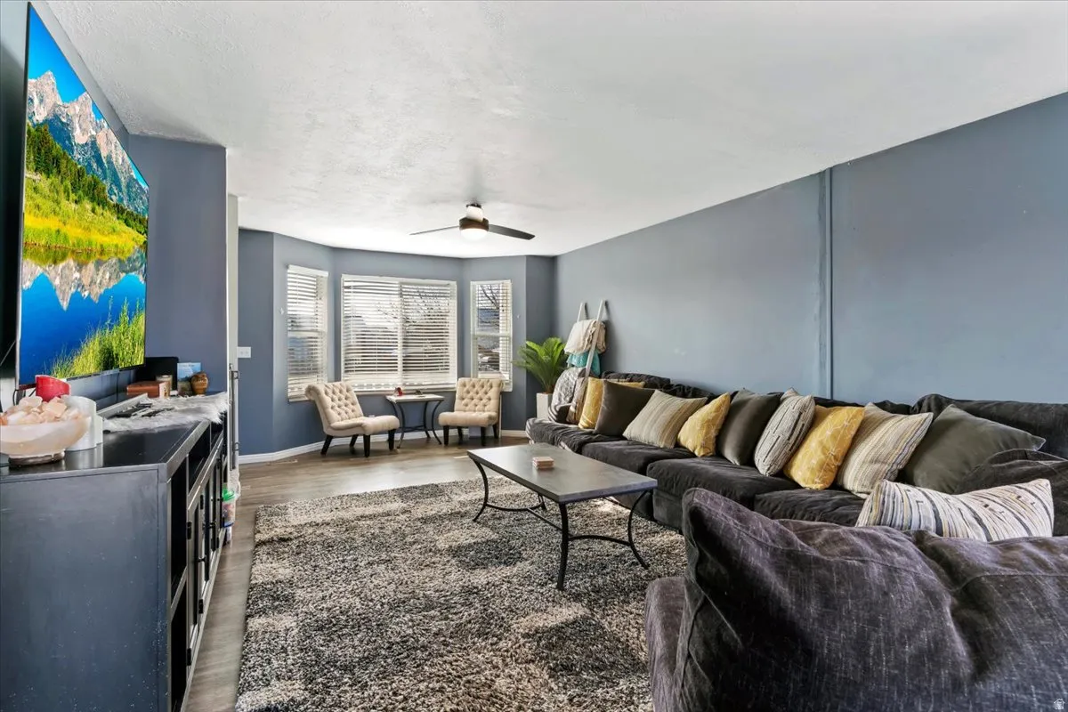 Living room with dark wood-style flooring and a ceiling fan