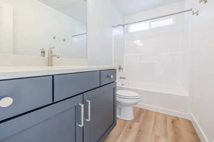 Bathroom featuring a modern vanity with gray cabinetry, a light-toned countertop, and a brushed nickel faucet