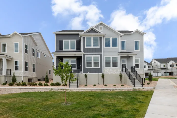 Contemporary townhome exterior featuring multi-toned siding, white trim, and a stone facade accent
