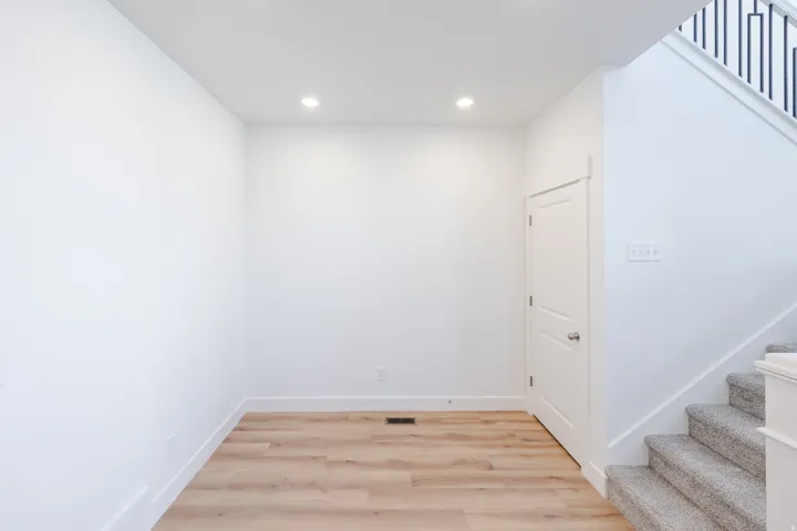 Open space featuring wood-finish flooring, recessed lighting, and white baseboards
