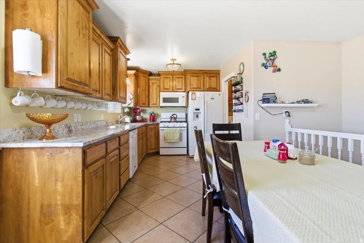 Kitchen featuring white appliances, brown cabinetry, and light tile patterned floors
