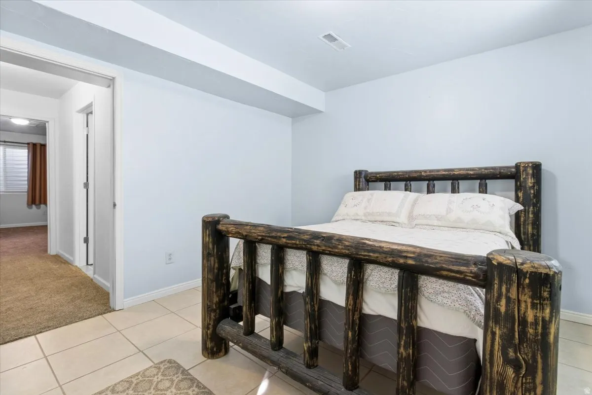 Bedroom with light tile patterned flooring and light colored carpet