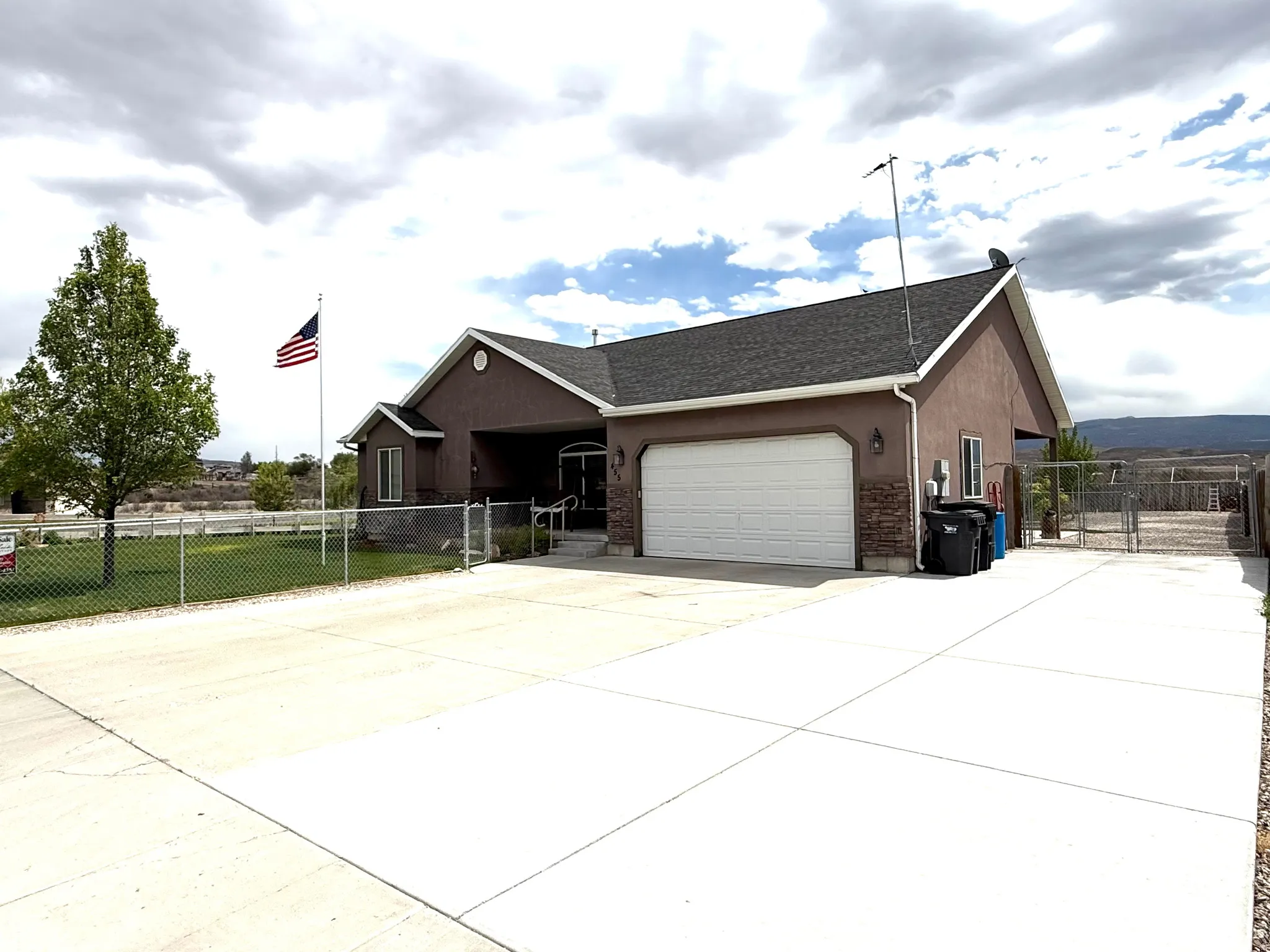 Exterior features a brown stucco finish with stone accents and a dark shingle roof