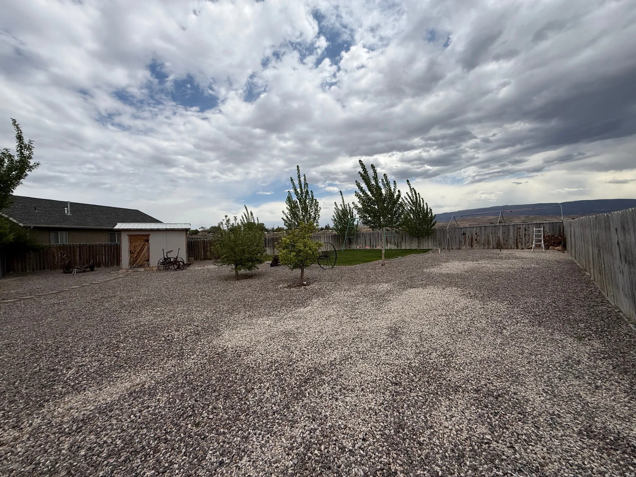 Expansive outdoor space featuring a gravel ground cover and a wooden privacy fence