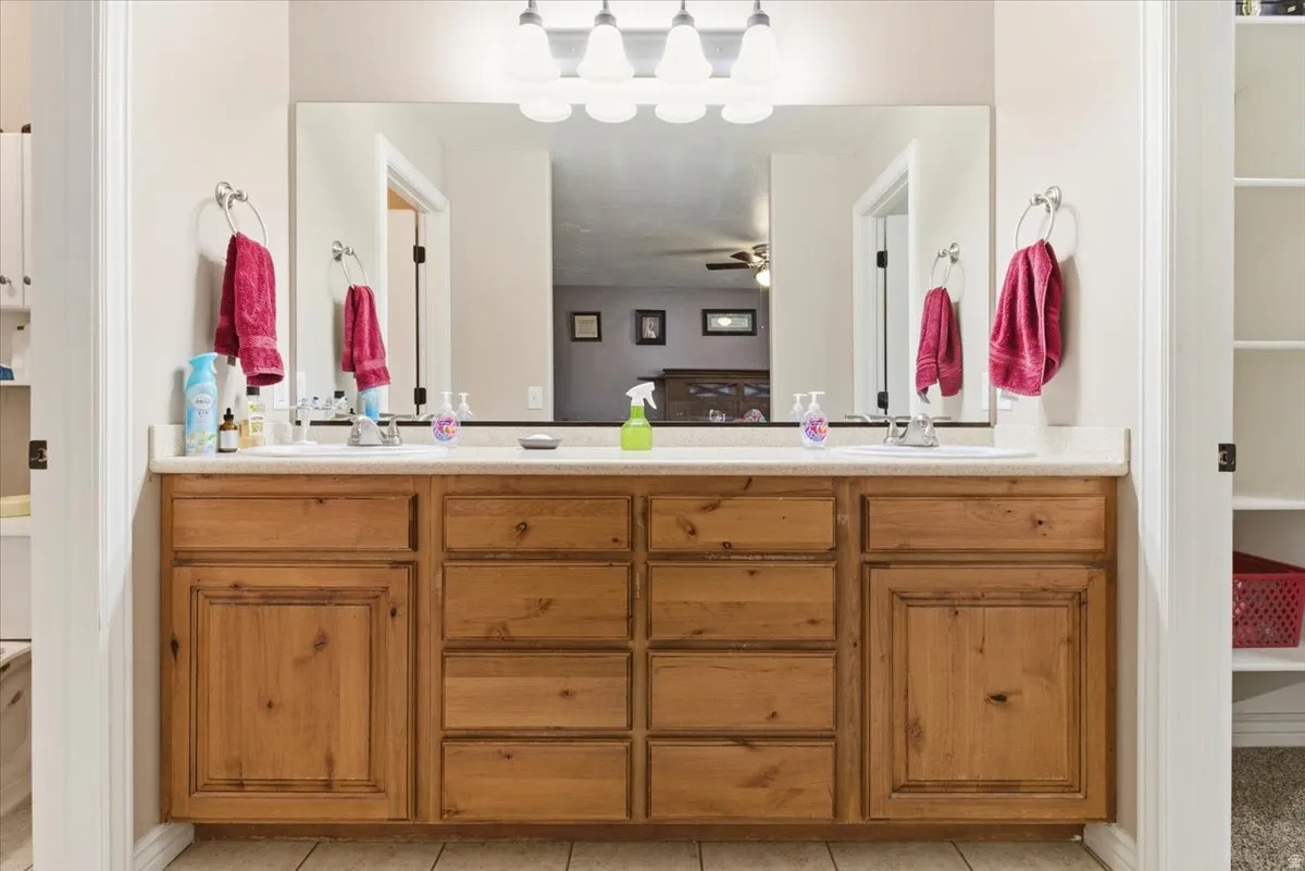 Bathroom with double vanity, light tile patterned floors, and a spacious closet
