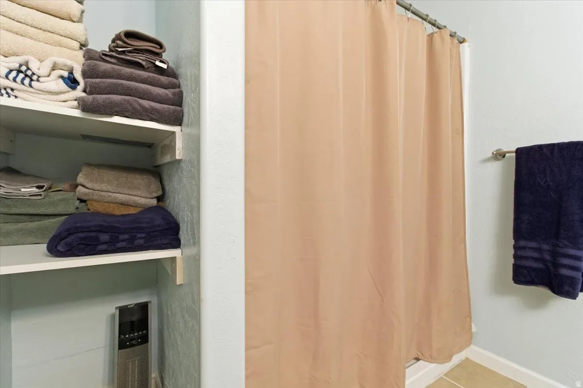 Full bath with a shower with shower curtain and tile patterned floors