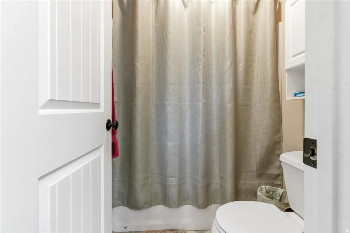 Full bathroom featuring curtained shower and toilet