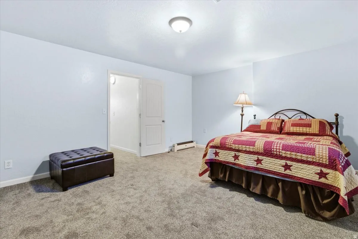 Carpeted bedroom with baseboards and a baseboard radiator