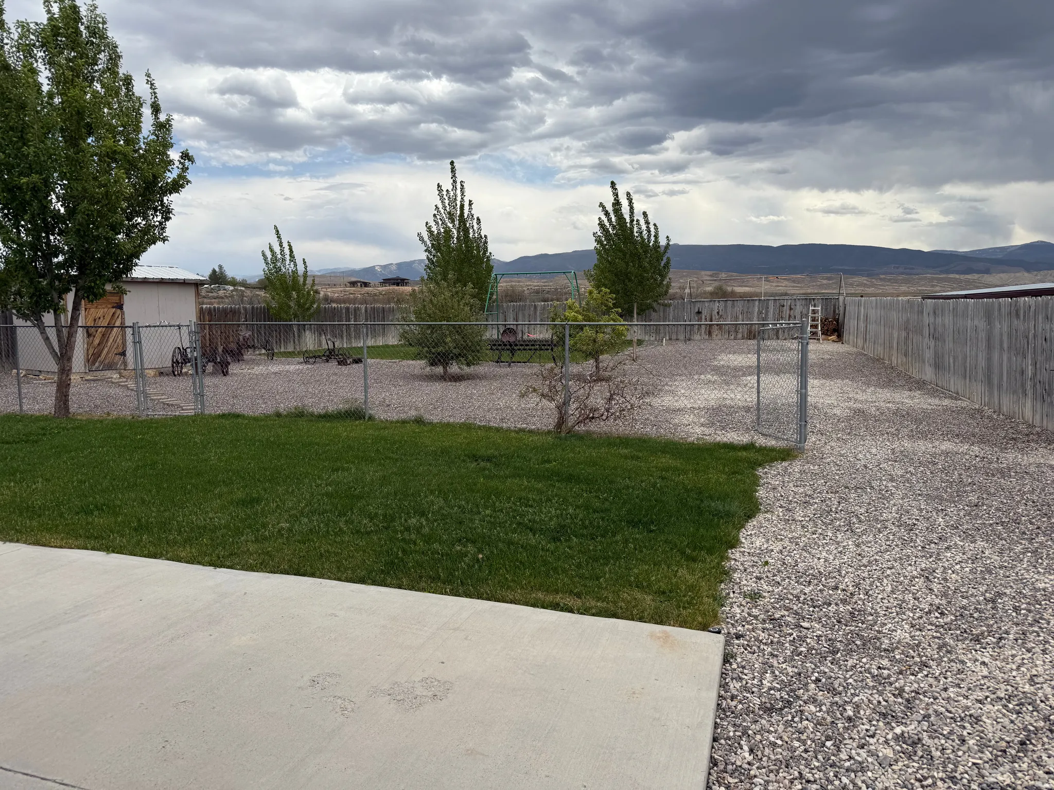 Expansive outdoor area featuring a concrete patio, manicured lawn, and a gravel-covered space