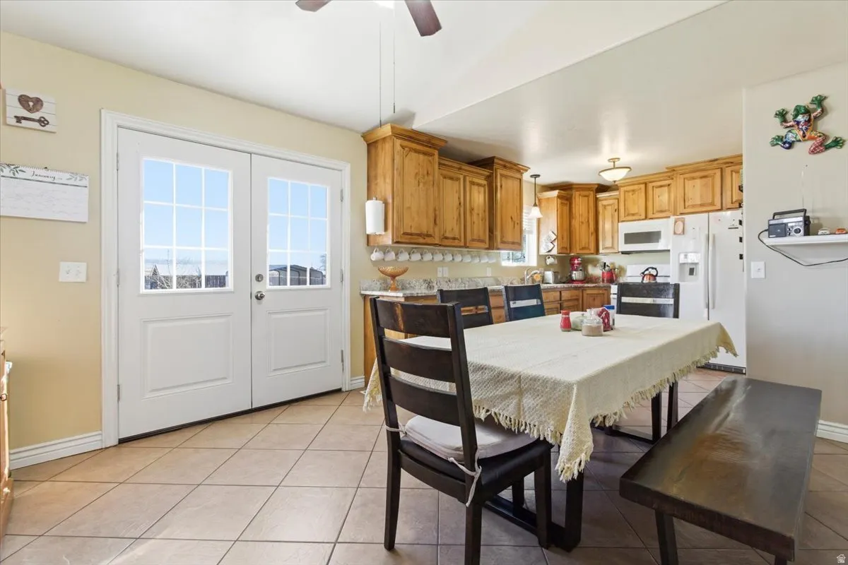 Dining space with light tile patterned flooring, french doors, and ceiling fan