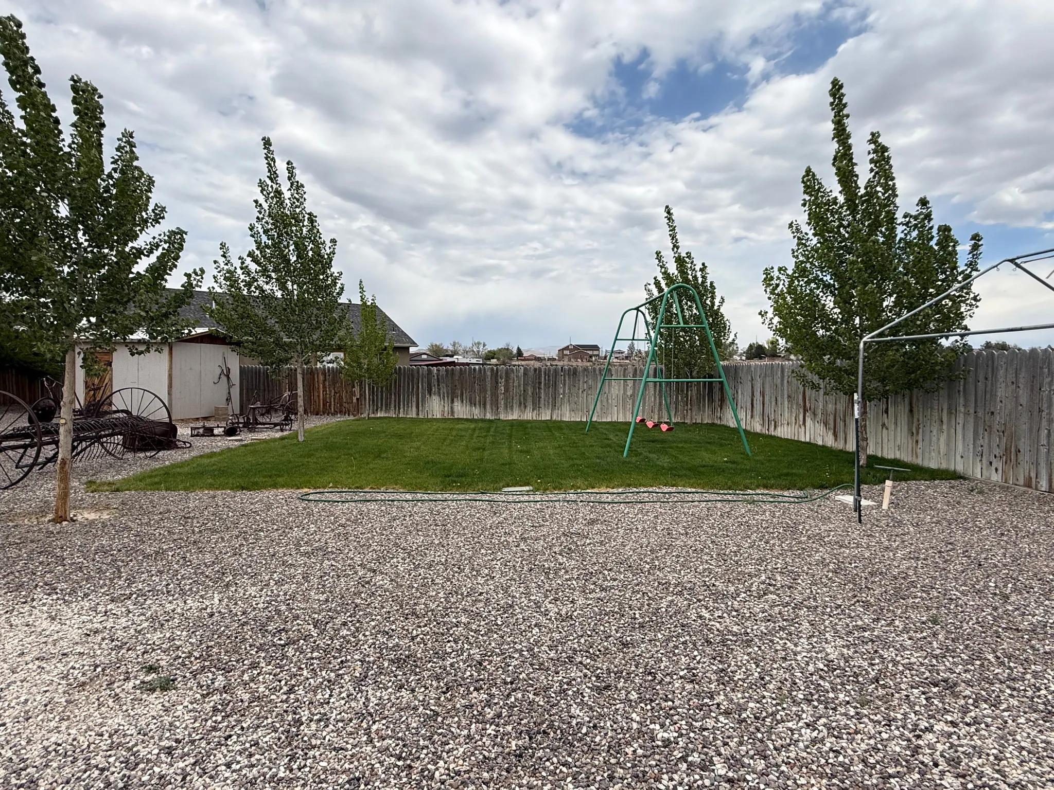 Expansive backyard featuring a gravel patio area and a manicured lawn