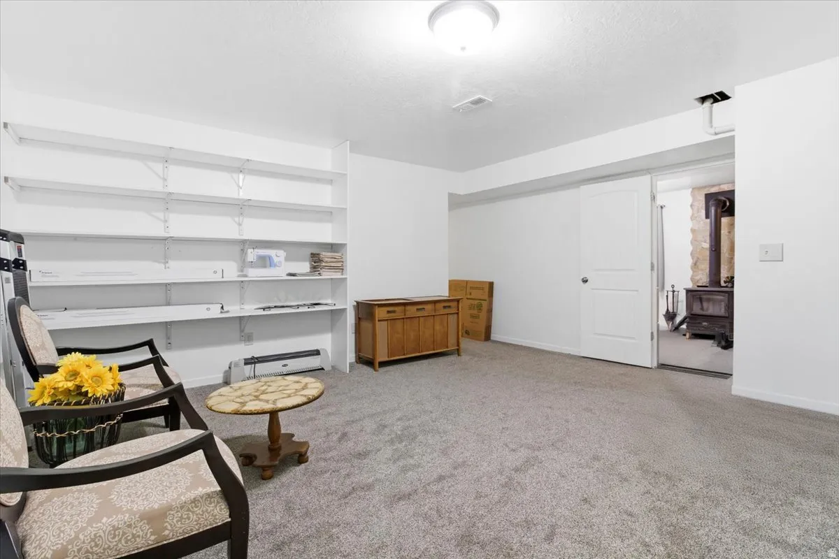 Living area featuring a wood stove, carpet, a baseboard radiator, and a textured ceiling