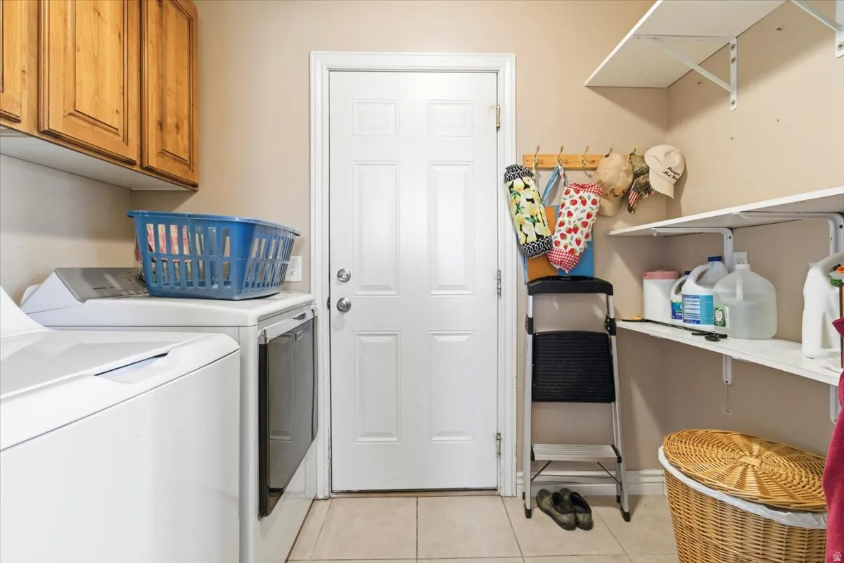 Washroom with washer and dryer, light tile patterned flooring, and cabinet space