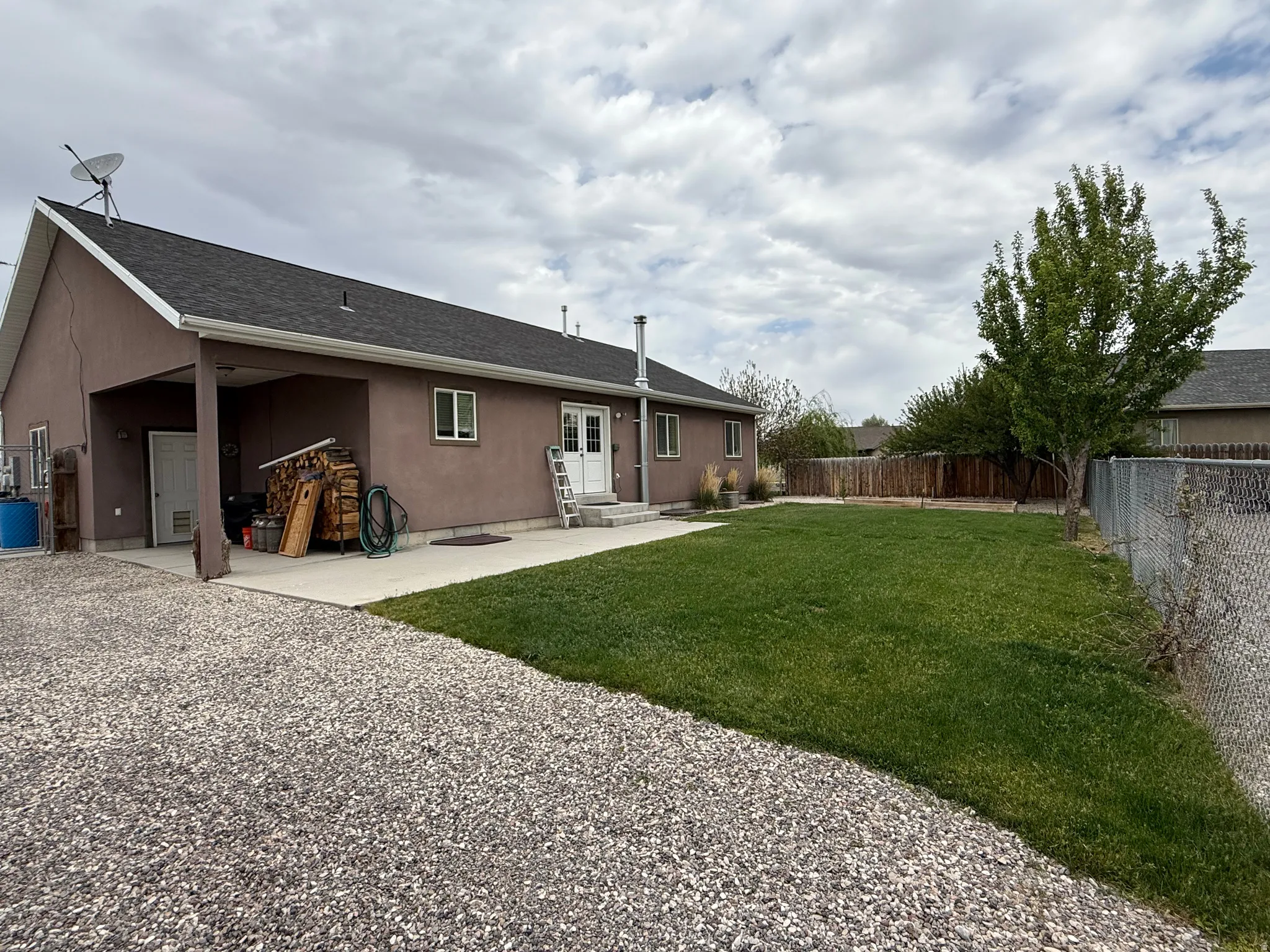 Spacious backyard featuring a substantial lawn area, a mature tree, and perimeter fencing