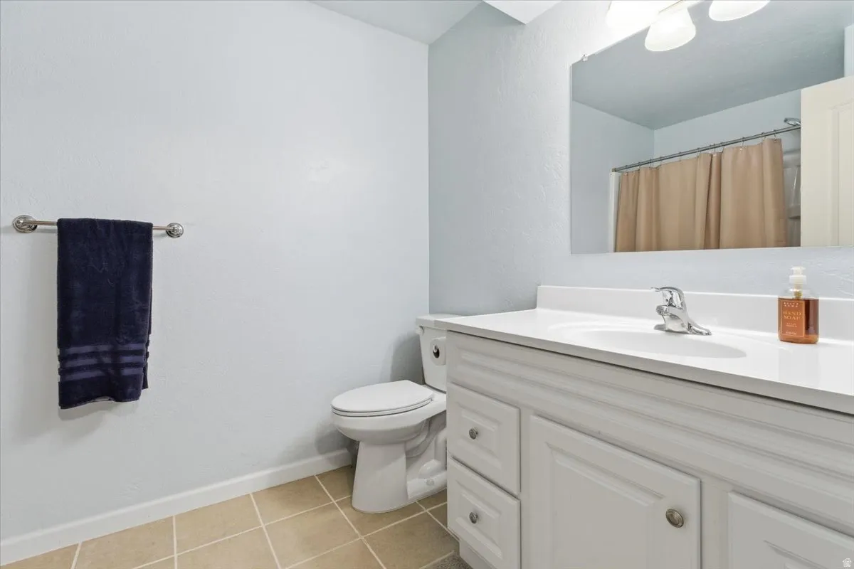 Bathroom with vanity, light tile patterned floors, a shower with curtain, and a textured wall