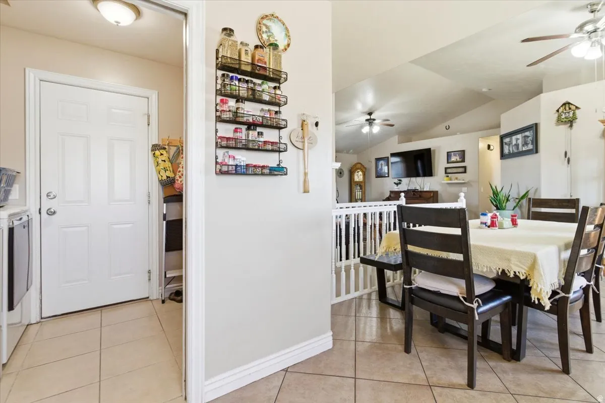 Dining area featuring a ceiling fan, vaulted ceiling, light tile patterned floors, and washer and clothes dryer