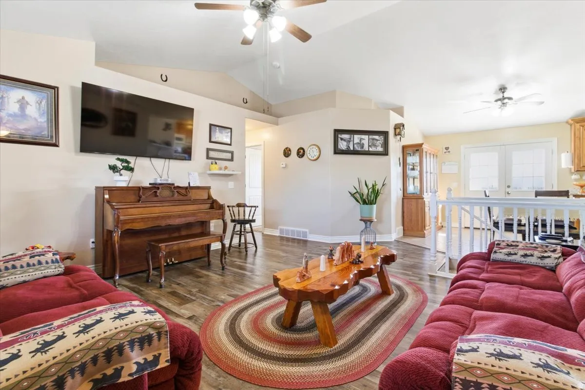 Living room featuring ceiling fan, lofted ceiling, and wood finished floors